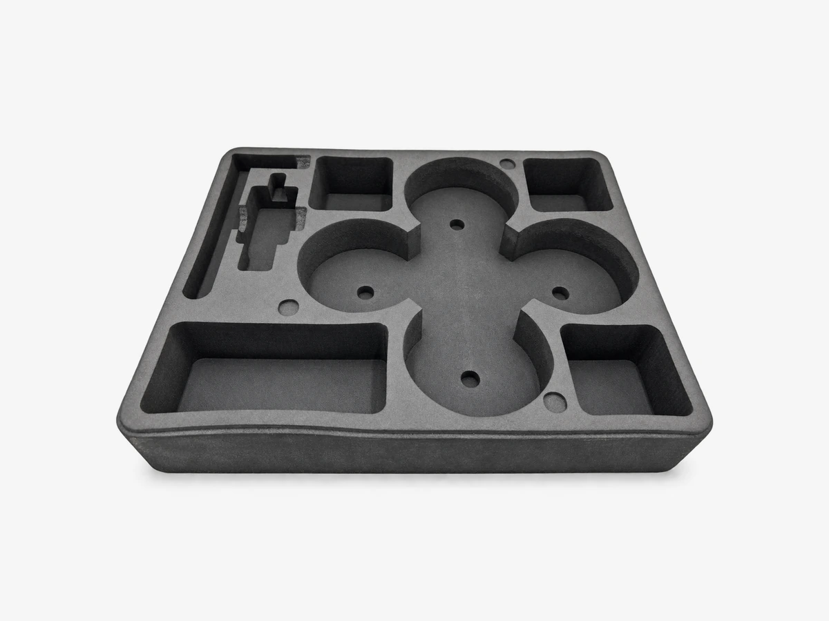 Illustration d’application adaptée : vue oblique d’un insert mousse EVA pour drone de 6 pouces et accessoires, avec logements circulaires reliés, poches rectangulaires et rainure latérale.