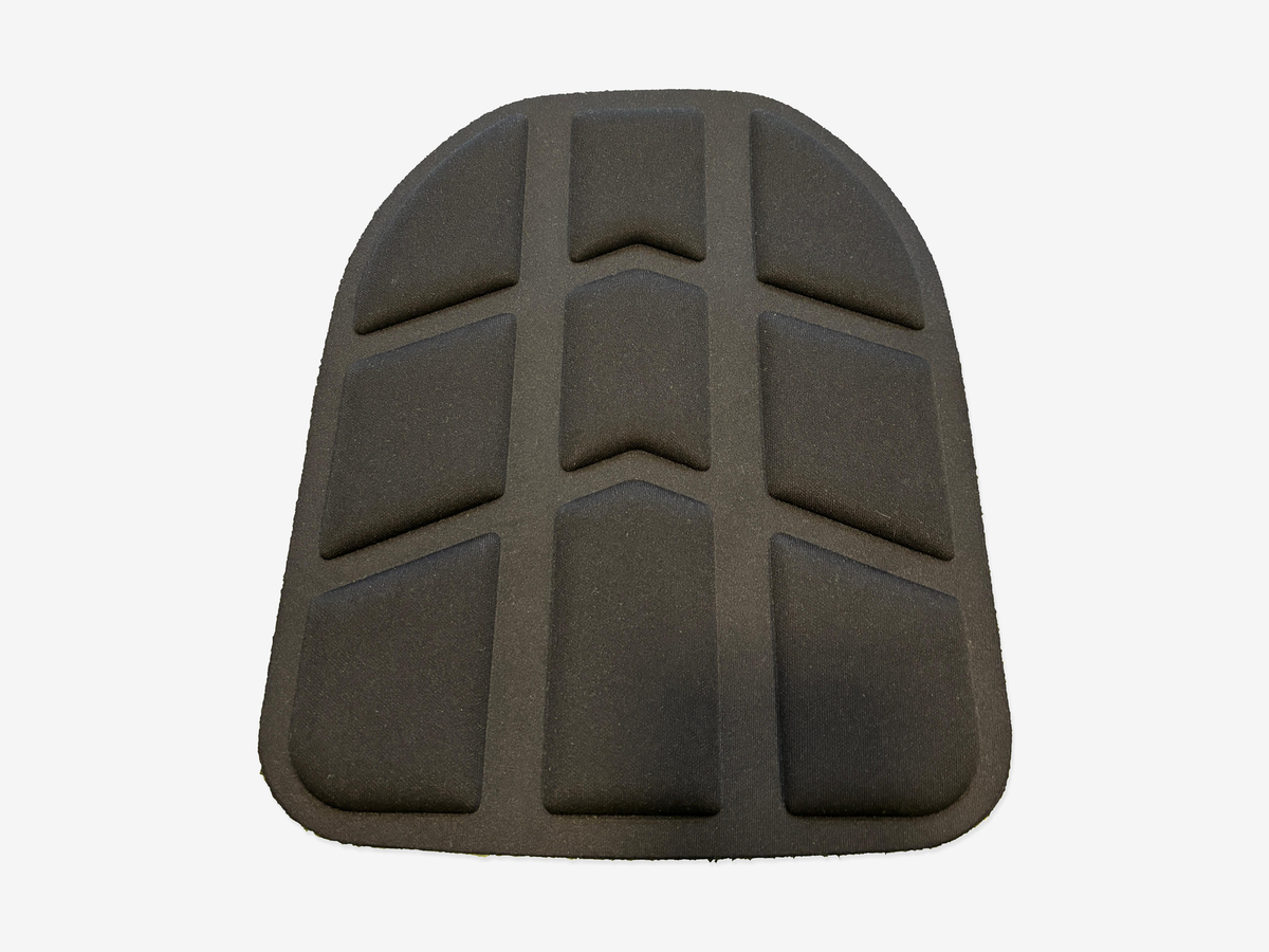 Front view of a black padded backpack back panel with nine raised sections in three columns on a light gray background.